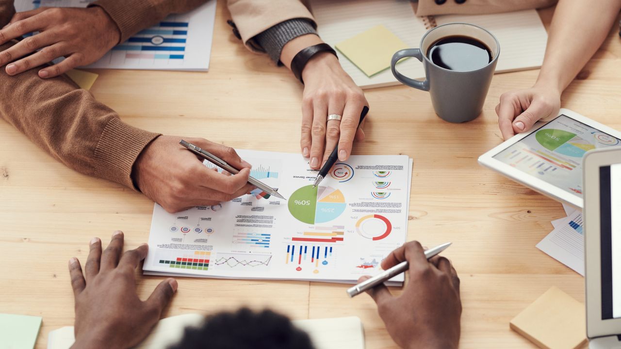 Hands reviewing printed charts and reports around a shared table